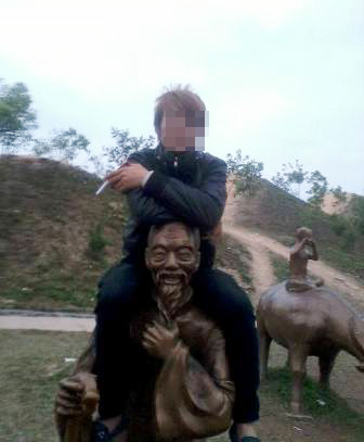 Người thanh niên hồ hởi ngồi trên vai tượng chụp ảnh